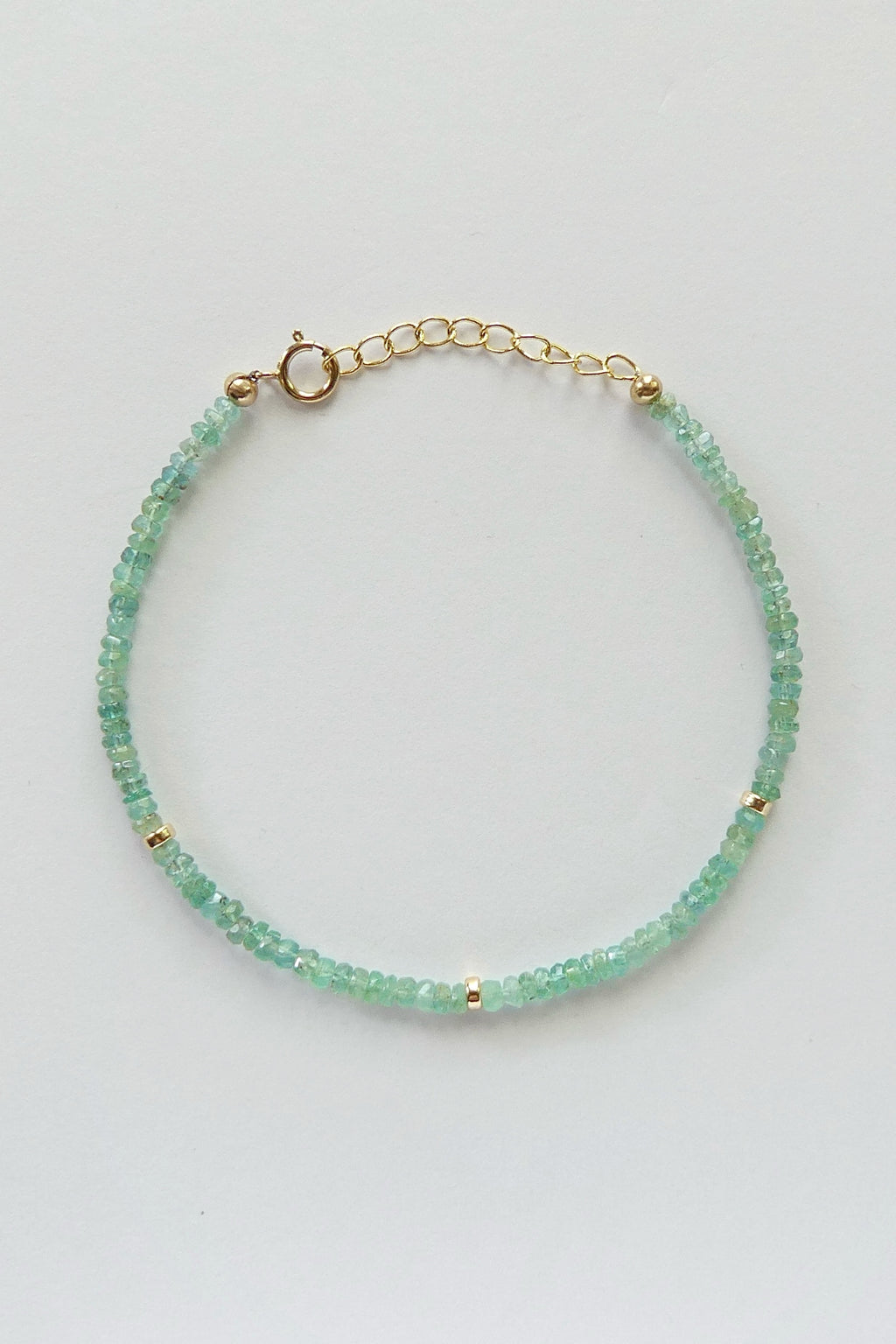 Adjustable gold-filled Zambian emerald bracelet with faceted 3mm green gemstone beads, shown laid flat with extender
