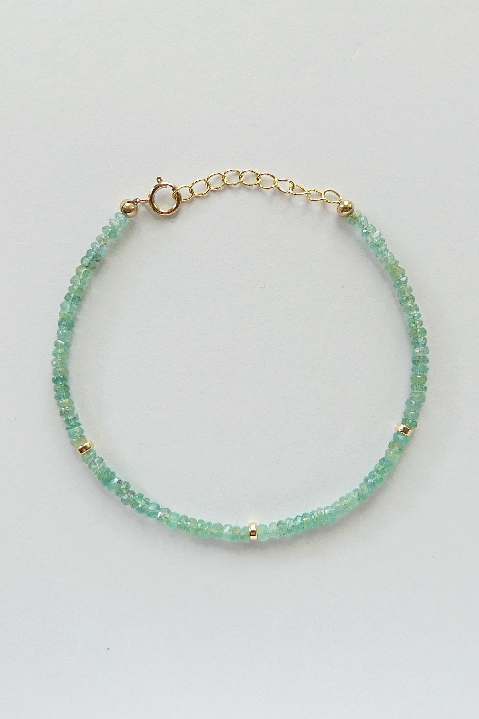 Adjustable gold-filled Zambian emerald bracelet with faceted 3mm green gemstone beads, shown laid flat with extender