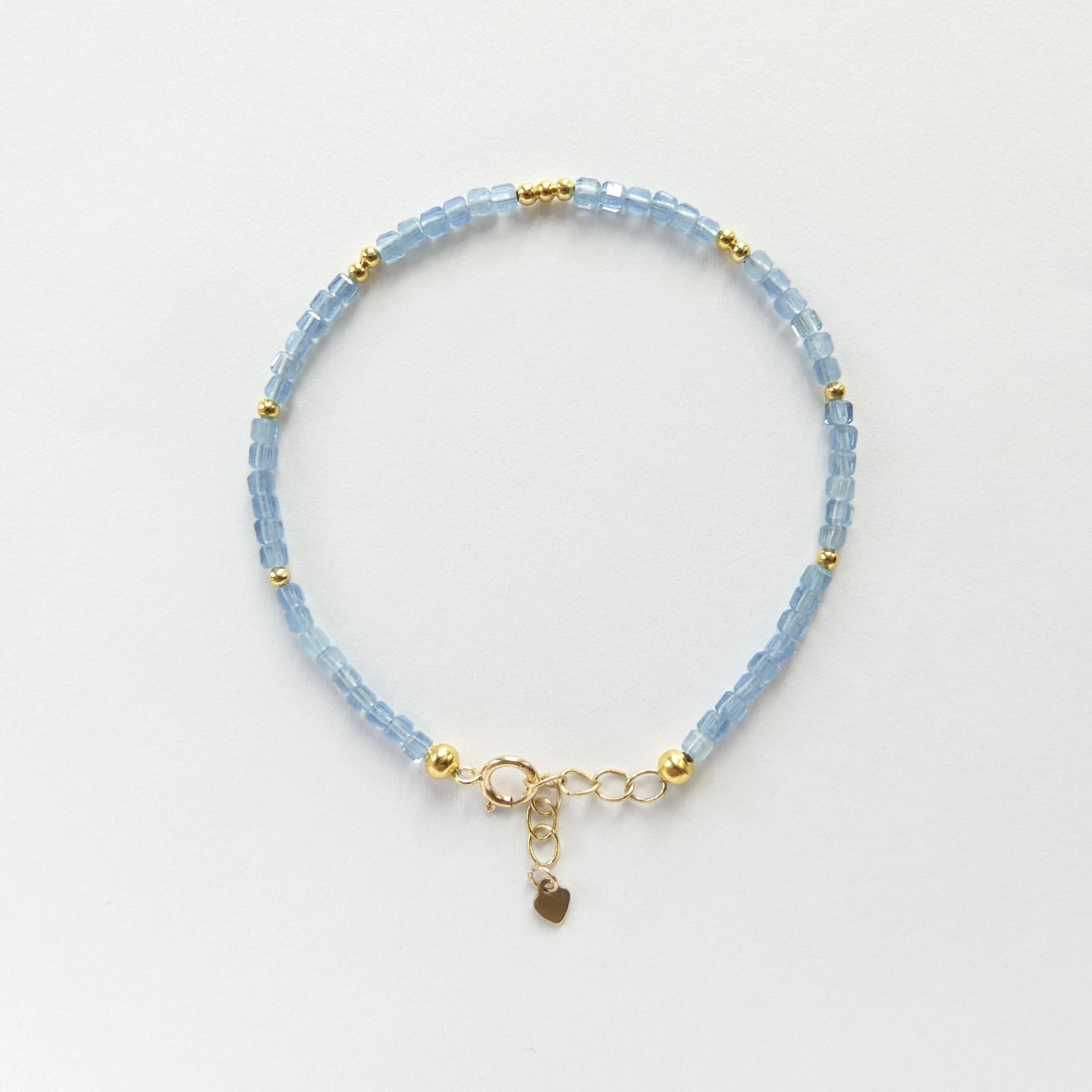 Vivid Blue aquamarine dainty beaded bracelet with gold accents on a light gray background