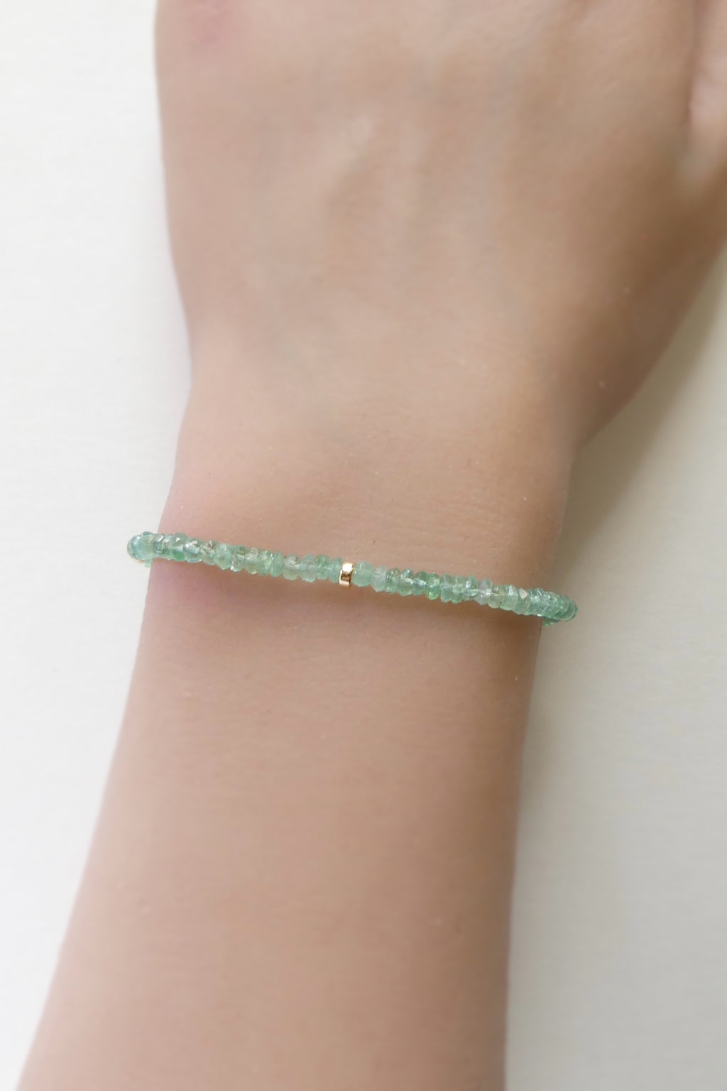 Adjustable gold-filled Zambian emerald bracelet with faceted 3mm green gemstone beads, shown laid flat with extender
