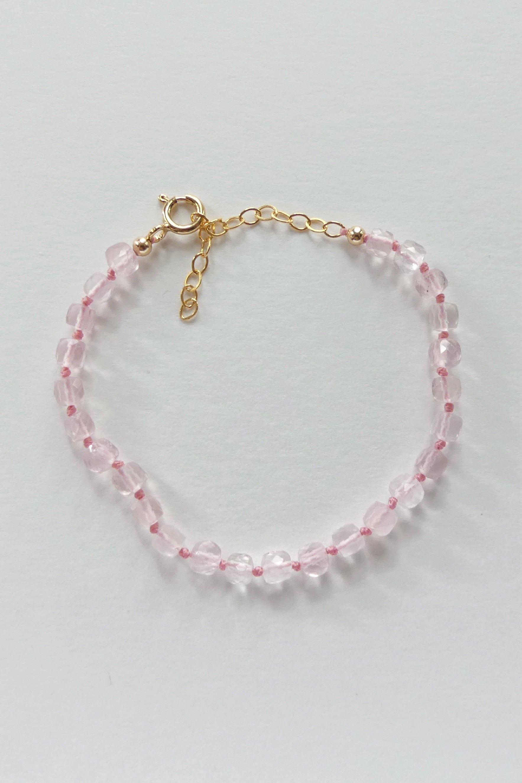 Adjustable rose quartz bracelet with 4mm faceted cube beads, hand-knotted on pink silk, finished with a gold-filled clasp and extender.