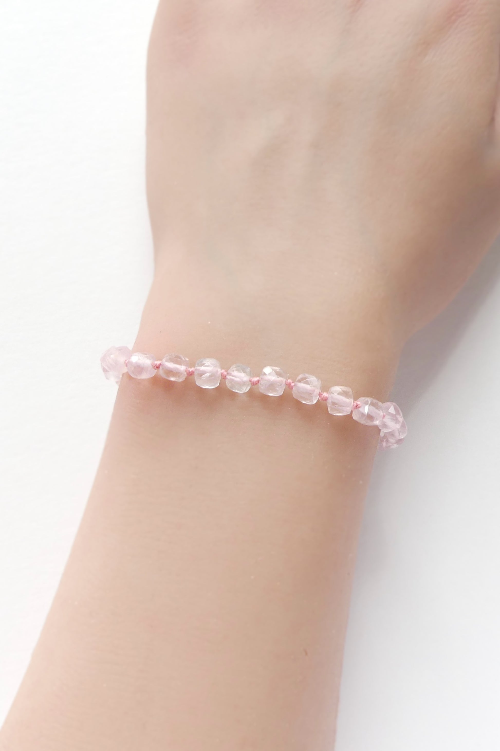 Adjustable rose quartz bracelet with 4mm faceted cube beads, hand-knotted on pink silk, finished with a gold-filled clasp and extender.