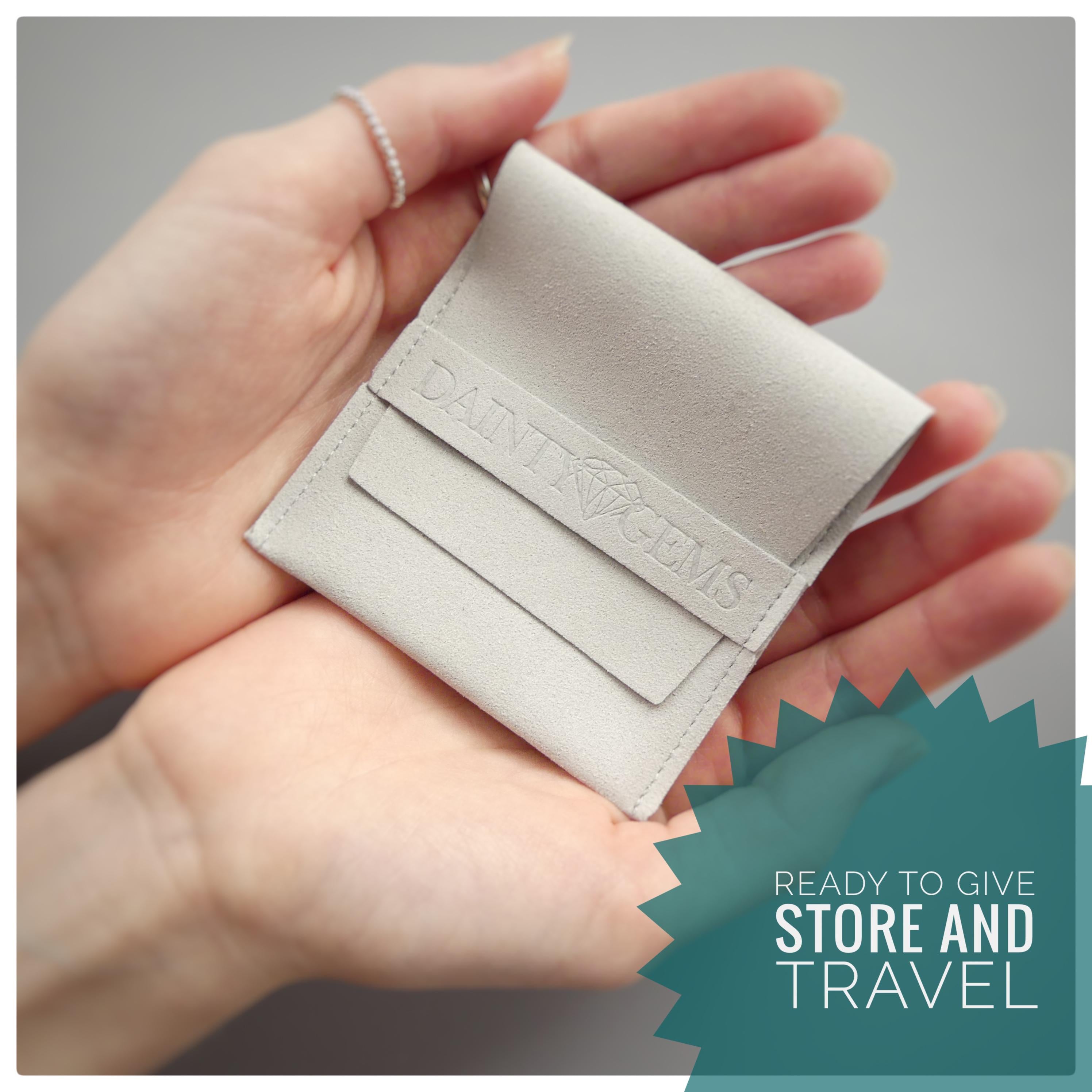 A person&#39;s hands holding a small, light-colored leather pouch with the text &quot;DAINI GEMS&quot; printed on it.