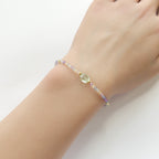 Multicolored beaded fluorite dainty bracelet on a wrist against a white background