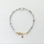 Multicolored beaded dainty fluorite bracelet with a gold clasp on a light gray background